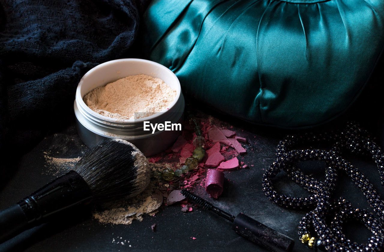 High angle view of beauty products by necklace on table