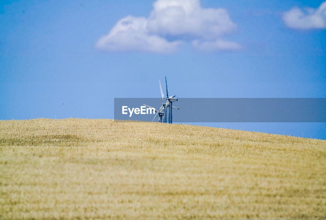 Wind turbines in field against sky