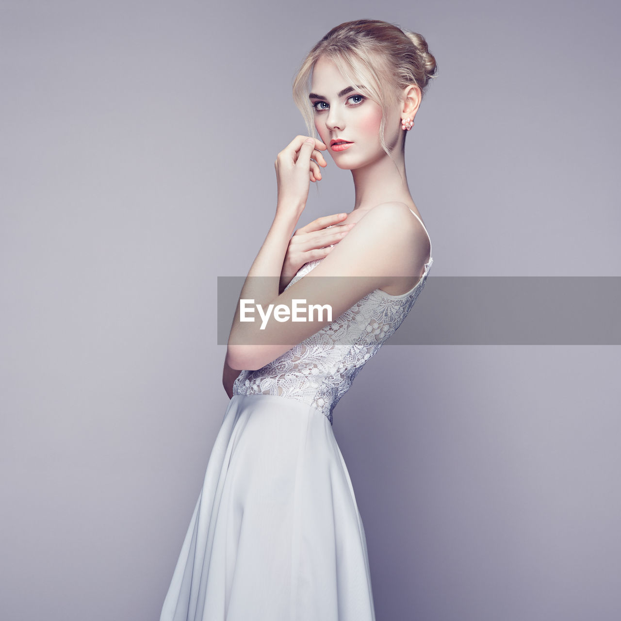 portrait of beautiful young woman standing against gray background