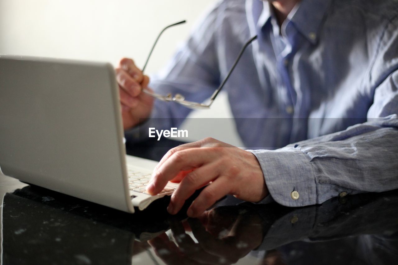 MIDSECTION OF PERSON WORKING WITH LAPTOP