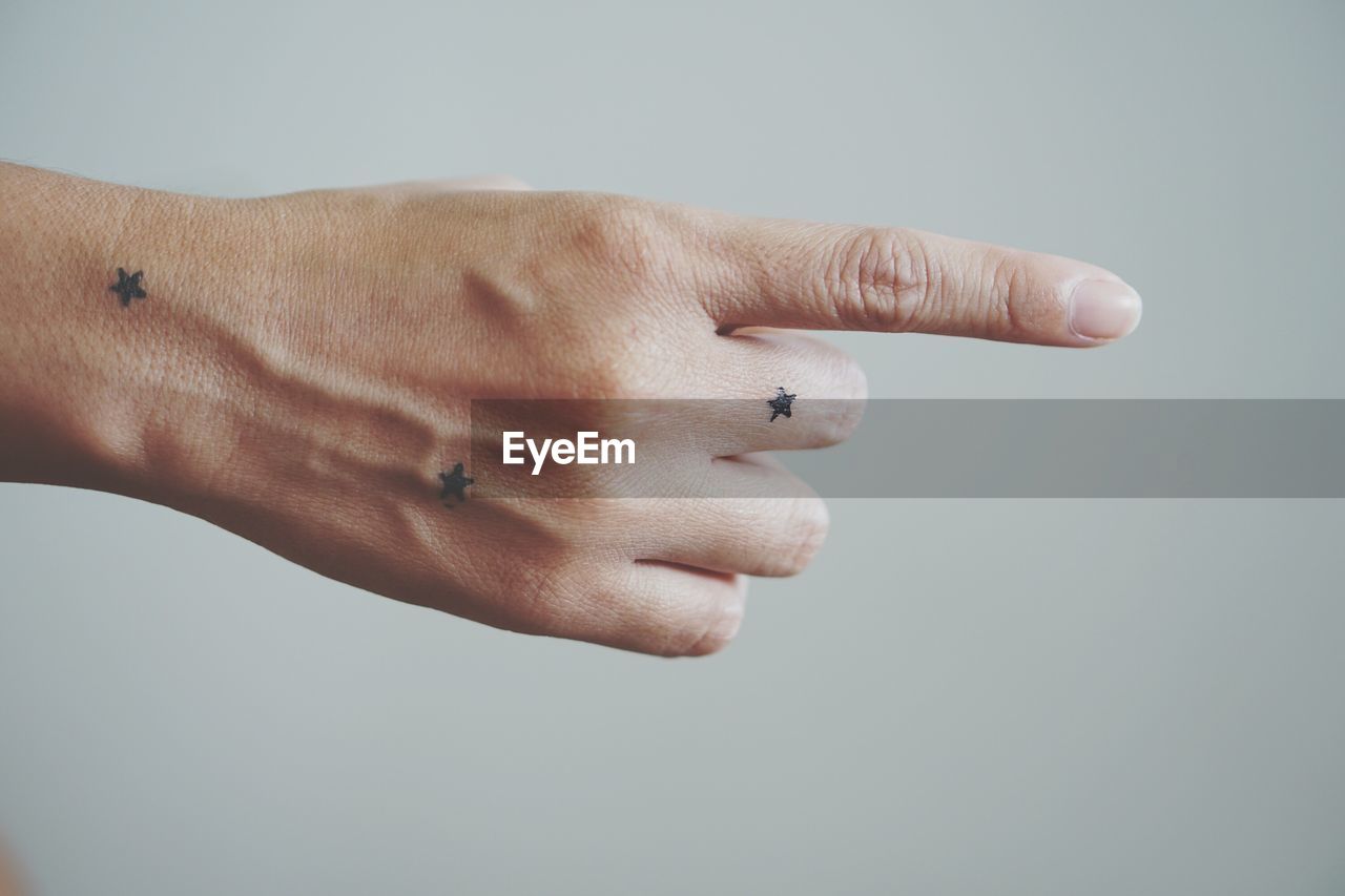 CLOSE-UP OF HAND HOLDING CIGARETTE AGAINST WHITE BACKGROUND