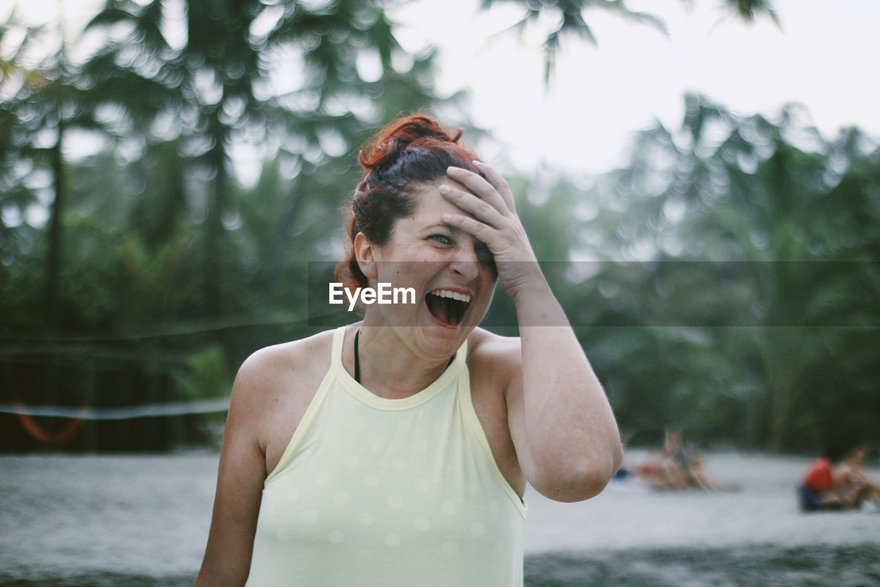 Close-up of mature woman laughing against tree