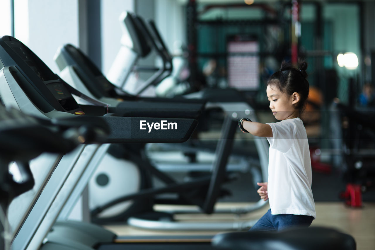 Side view of girl looking at smartwatch in gym