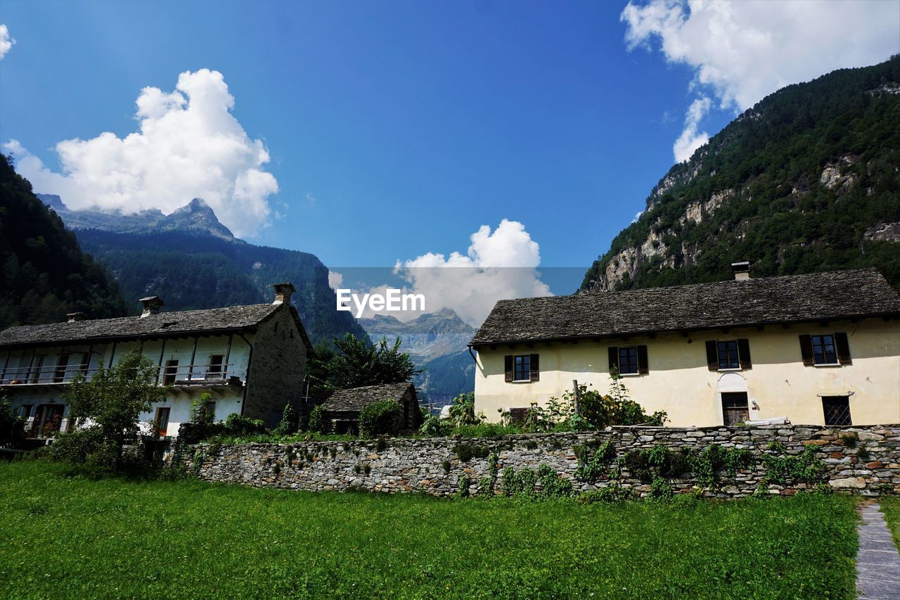 PANORAMIC SHOT OF BUILDINGS AGAINST MOUNTAINS