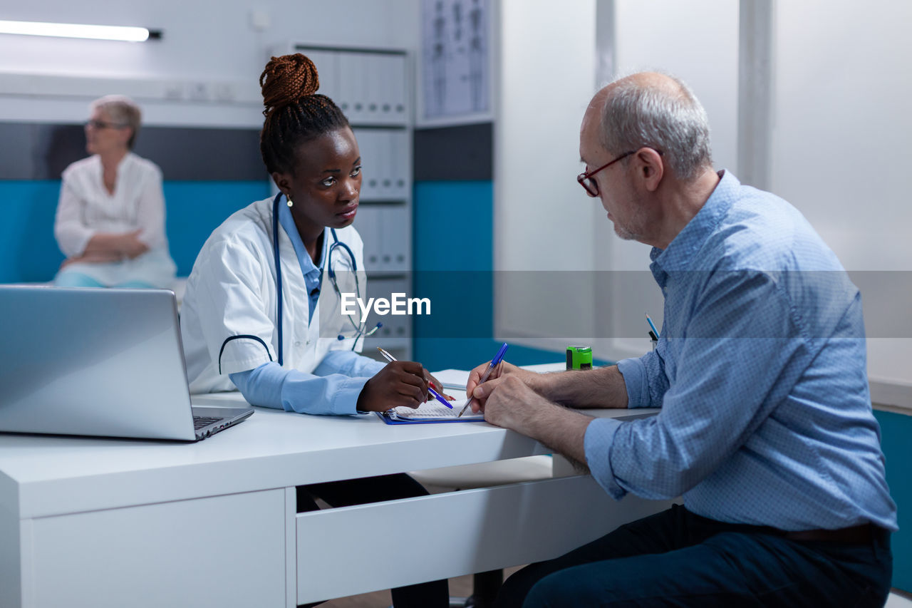 Doctor discussing with senior patient at clinic