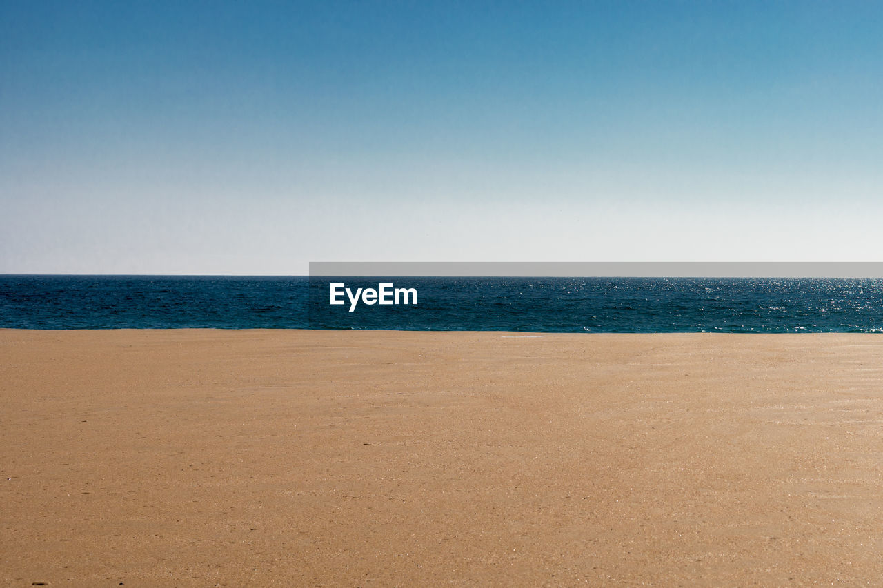 Scenic view of beach against clear blue sky