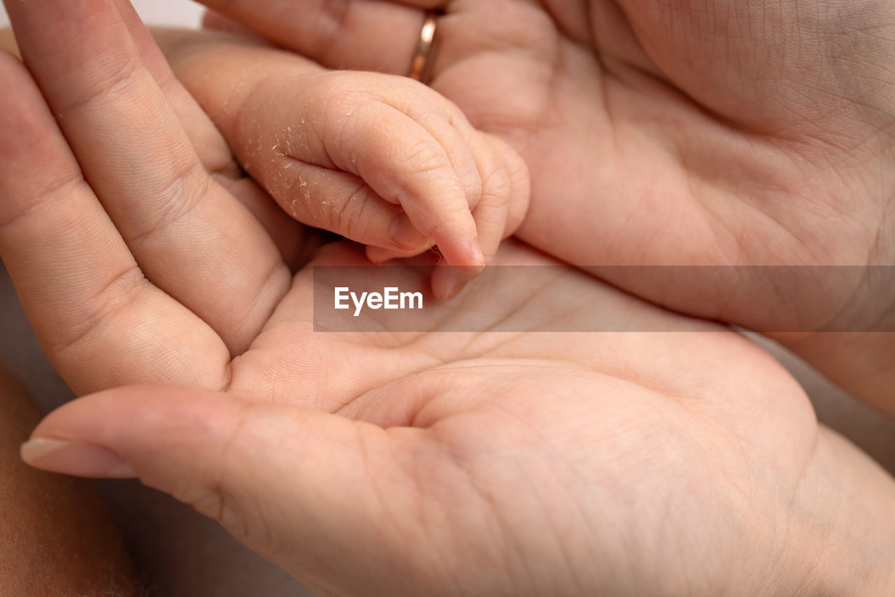 CLOSE-UP OF HANDS HOLDING BABY