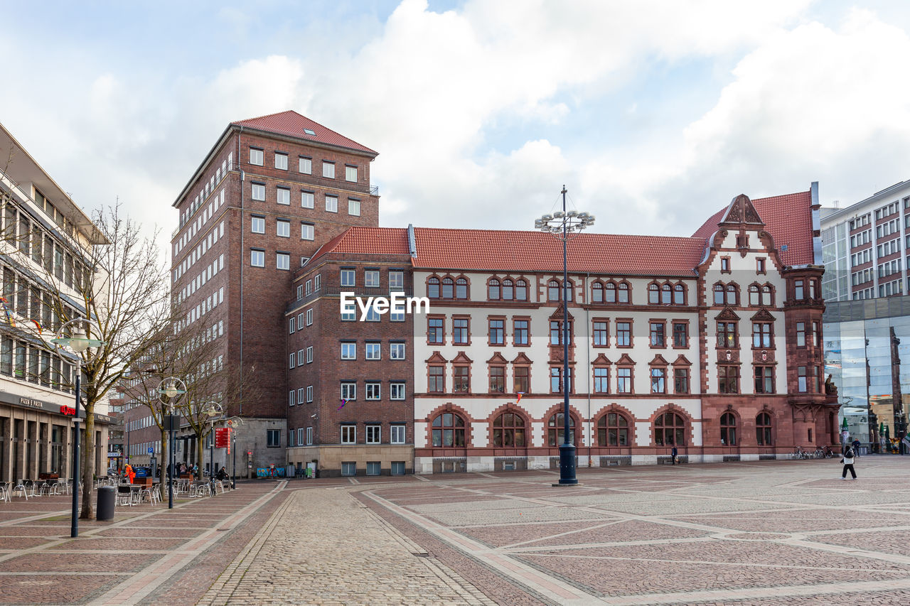 buildings in city against cloudy sky