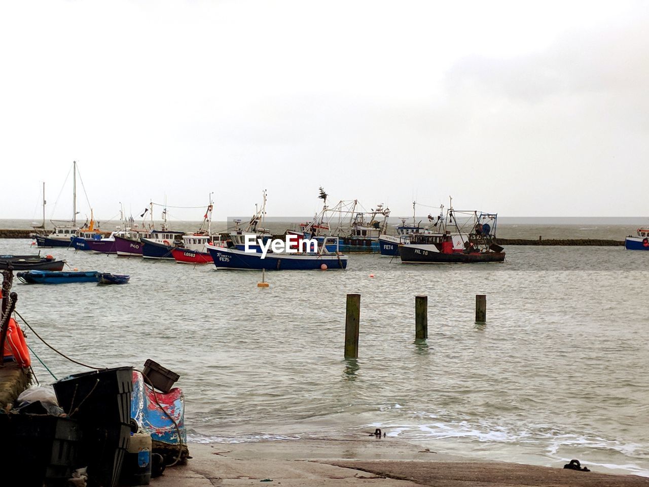 BOATS MOORED ON HARBOR AGAINST SKY