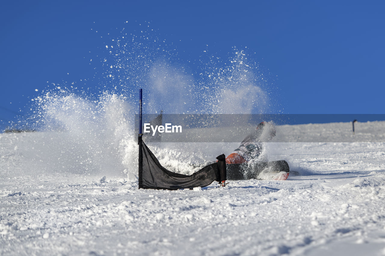 Girl falling on snow covered field against clear sky