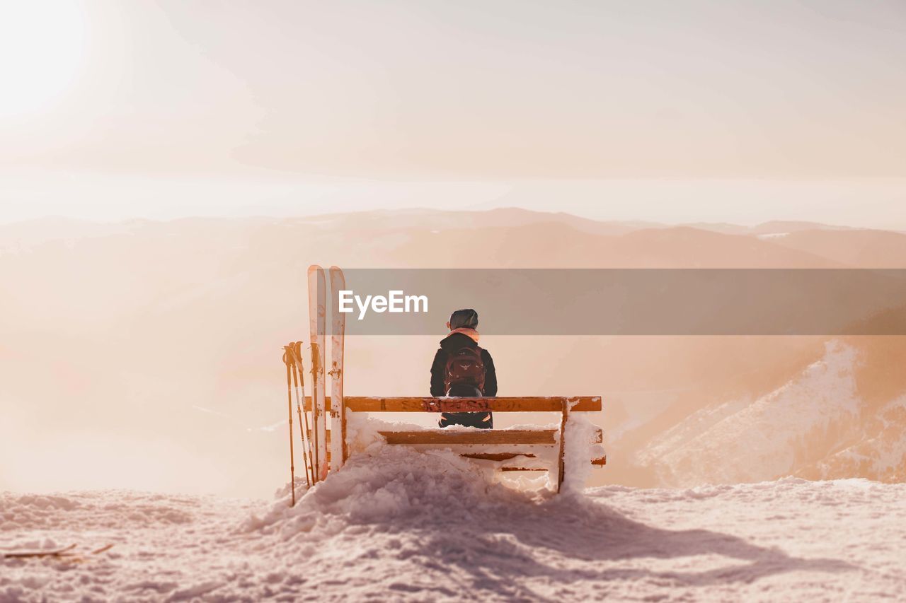 Rear view of girl sitting on snow covered mountain