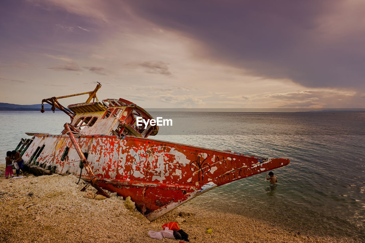 Ship moored on sea against sky at sunset