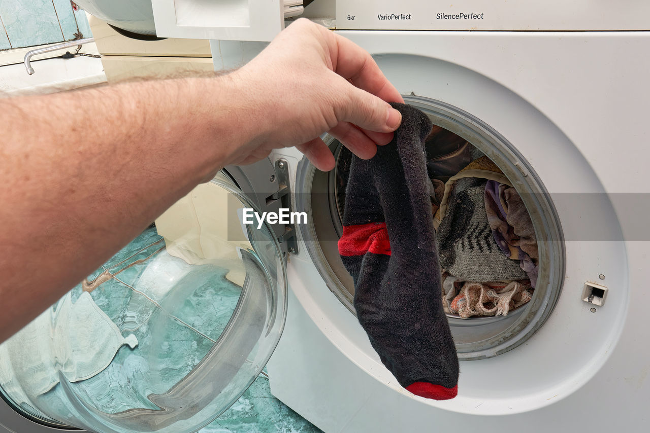 washing machine, clothes dryer, machinery, appliance, hand, laundry, household equipment, cleaning, one person, washing, housework, home appliance, domestic life, adult, lifestyles, indoors, chores, laundromat, technology, men, dryer, laundry room, major appliance, holding, hygiene