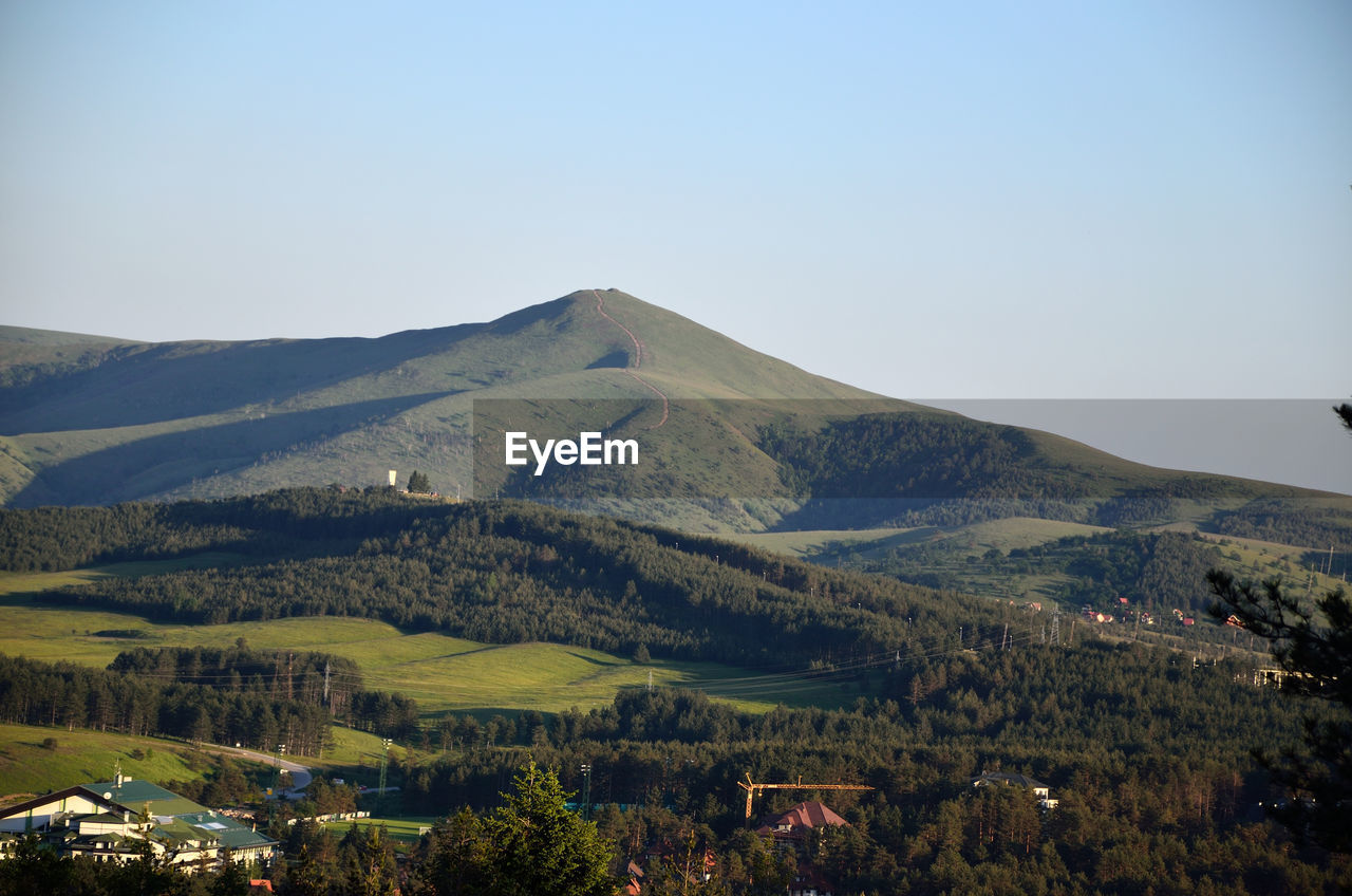 Mountains, hills, valleys with small houses in sunlight