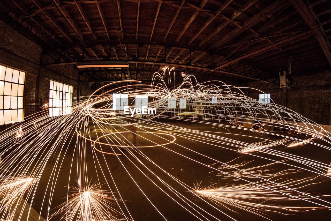 Person spinning firework in empty warehouse