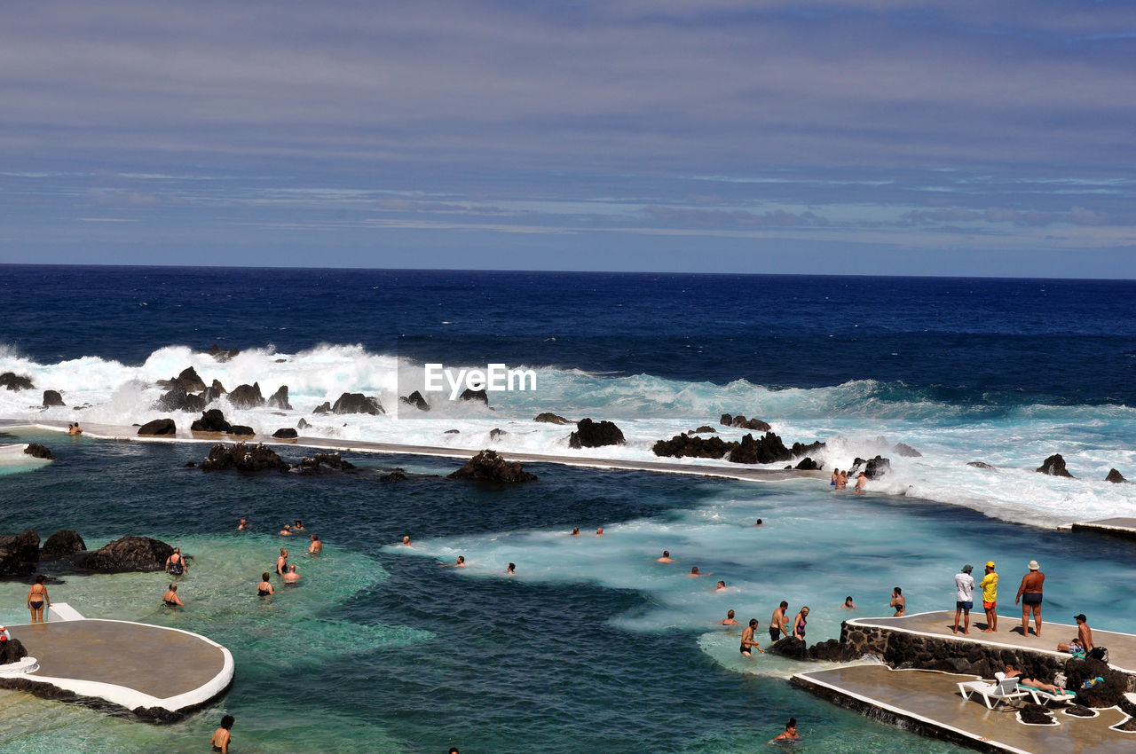 People enjoying in sea during summer against sky