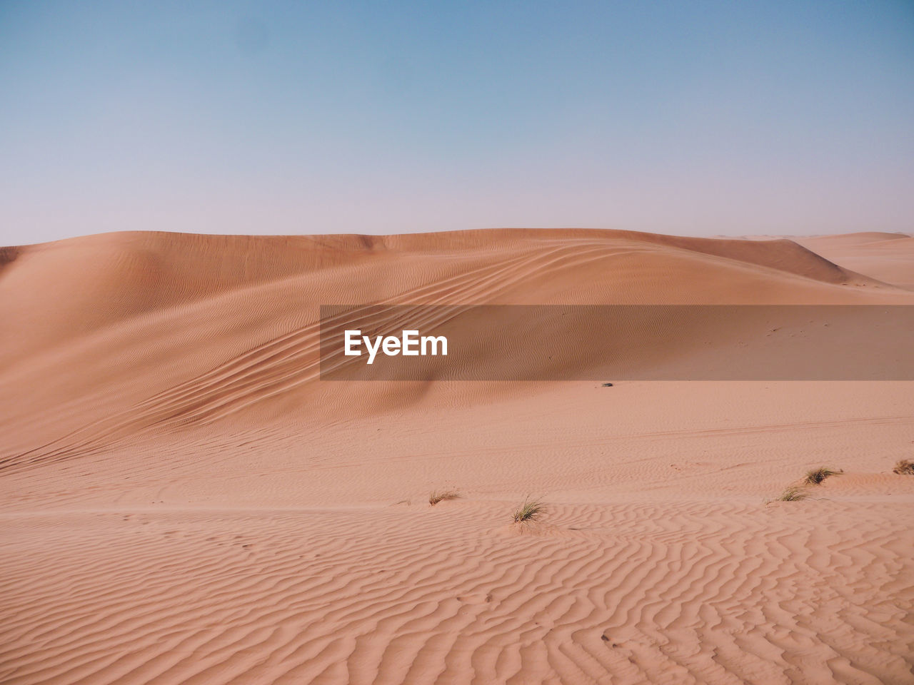 Sand dunes in desert against clear sky