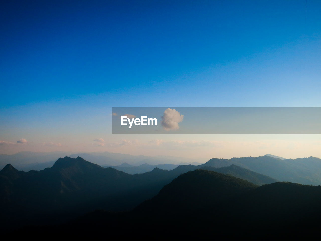 Scenic view of silhouette mountains against blue sky