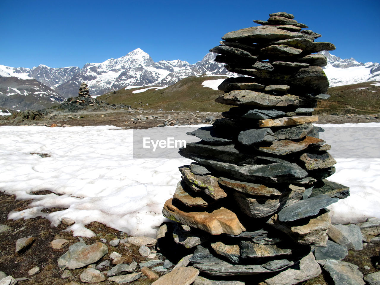 STACK OF ROCKS ON SNOW COVERED MOUNTAIN