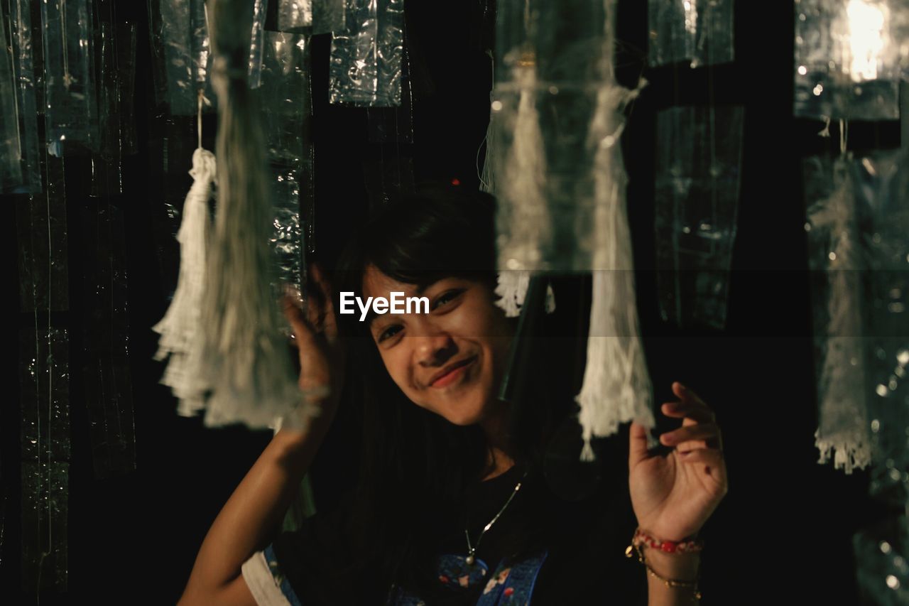 Portrait of smiling young woman amidst plastics in darkroom