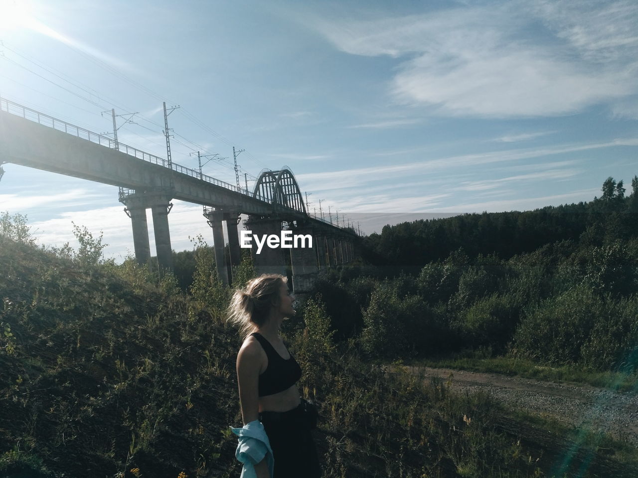 Side view of woman standing on field against sky