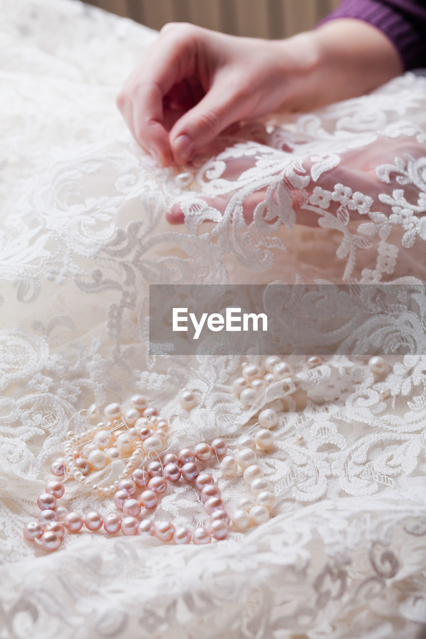 Cropped hands of woman stitching wedding dress