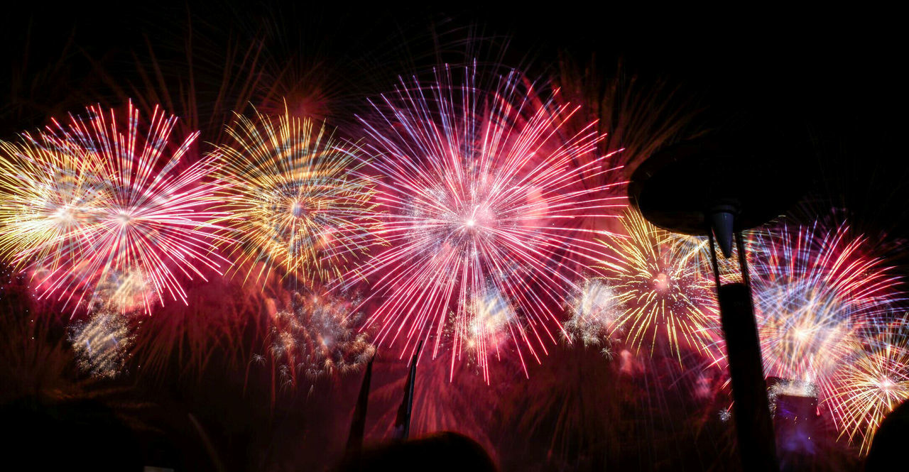 LOW ANGLE VIEW OF ILLUMINATED FIREWORK DISPLAY AT NIGHT