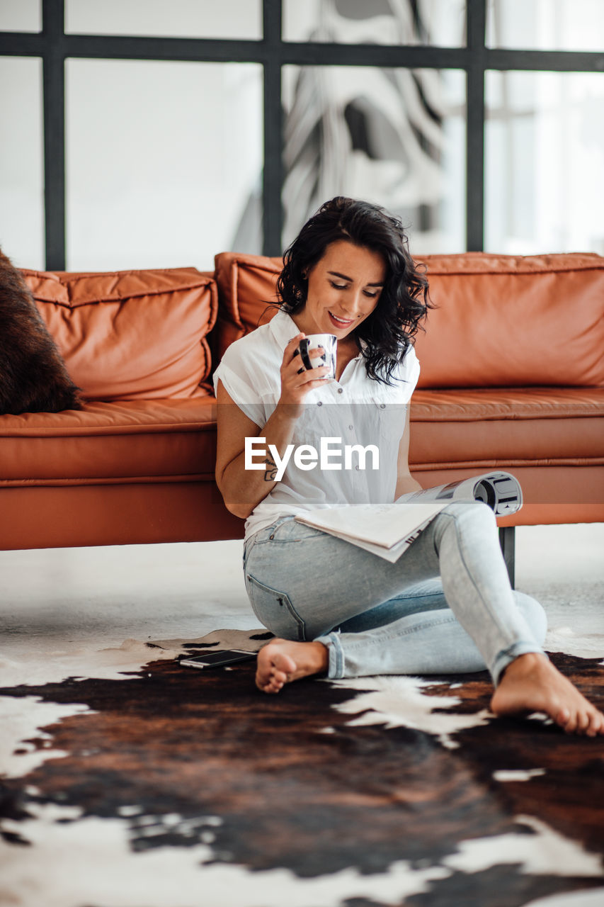 Woman reading magazine while having coffee at home