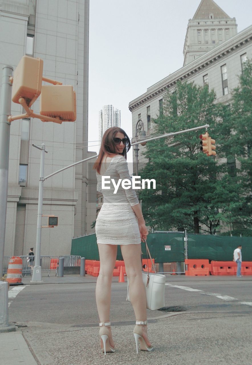 Full length of young woman standing against building