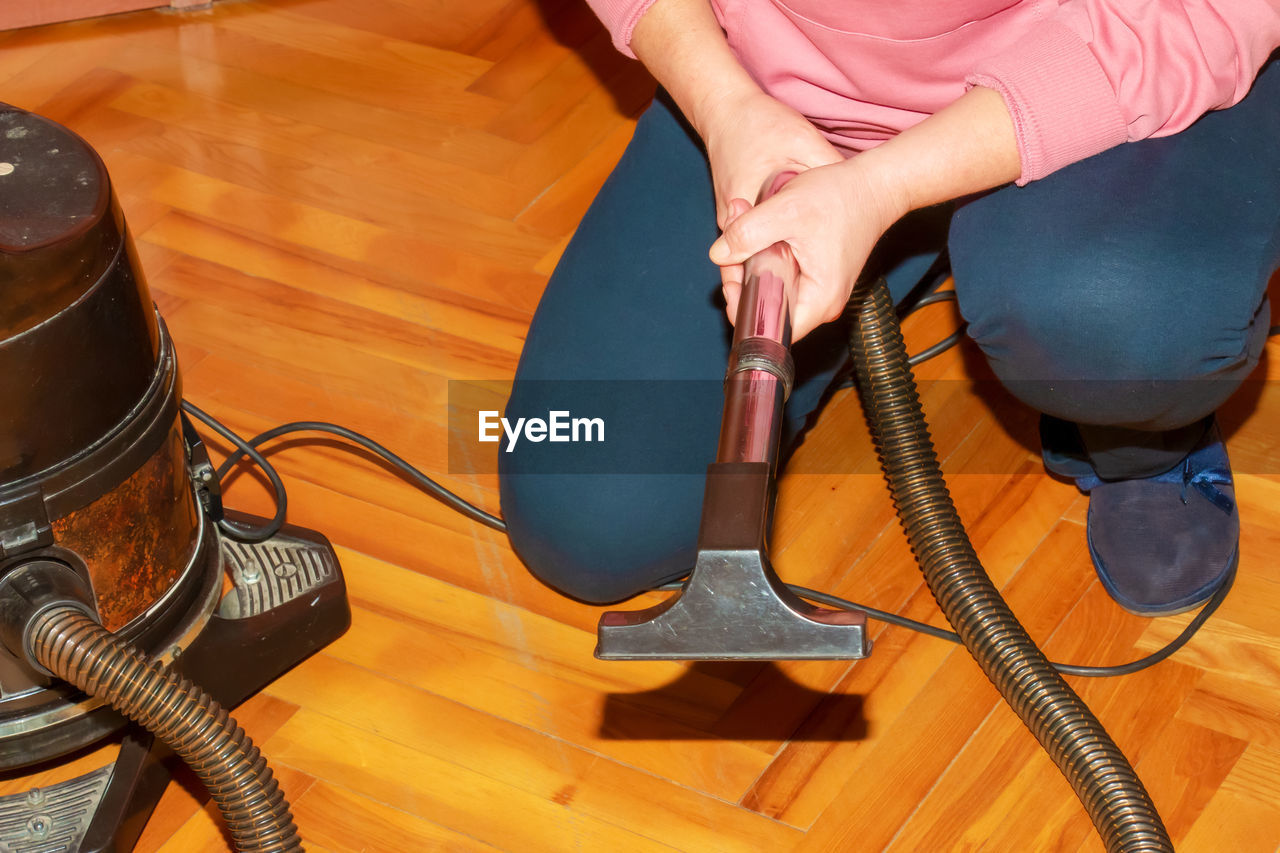 A middle-aged woman collects a vacuum cleaner for house cleaning.