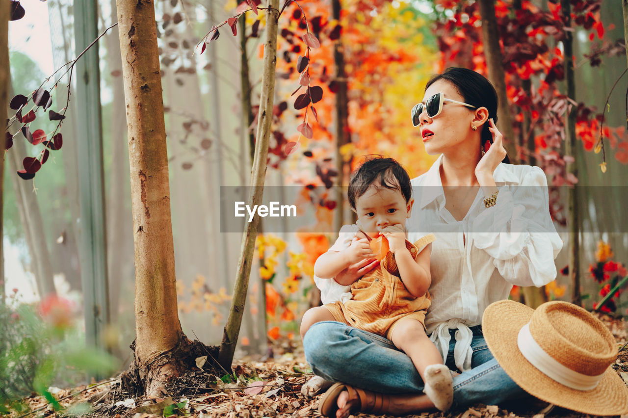 Mother and son sitting at forest during autumn