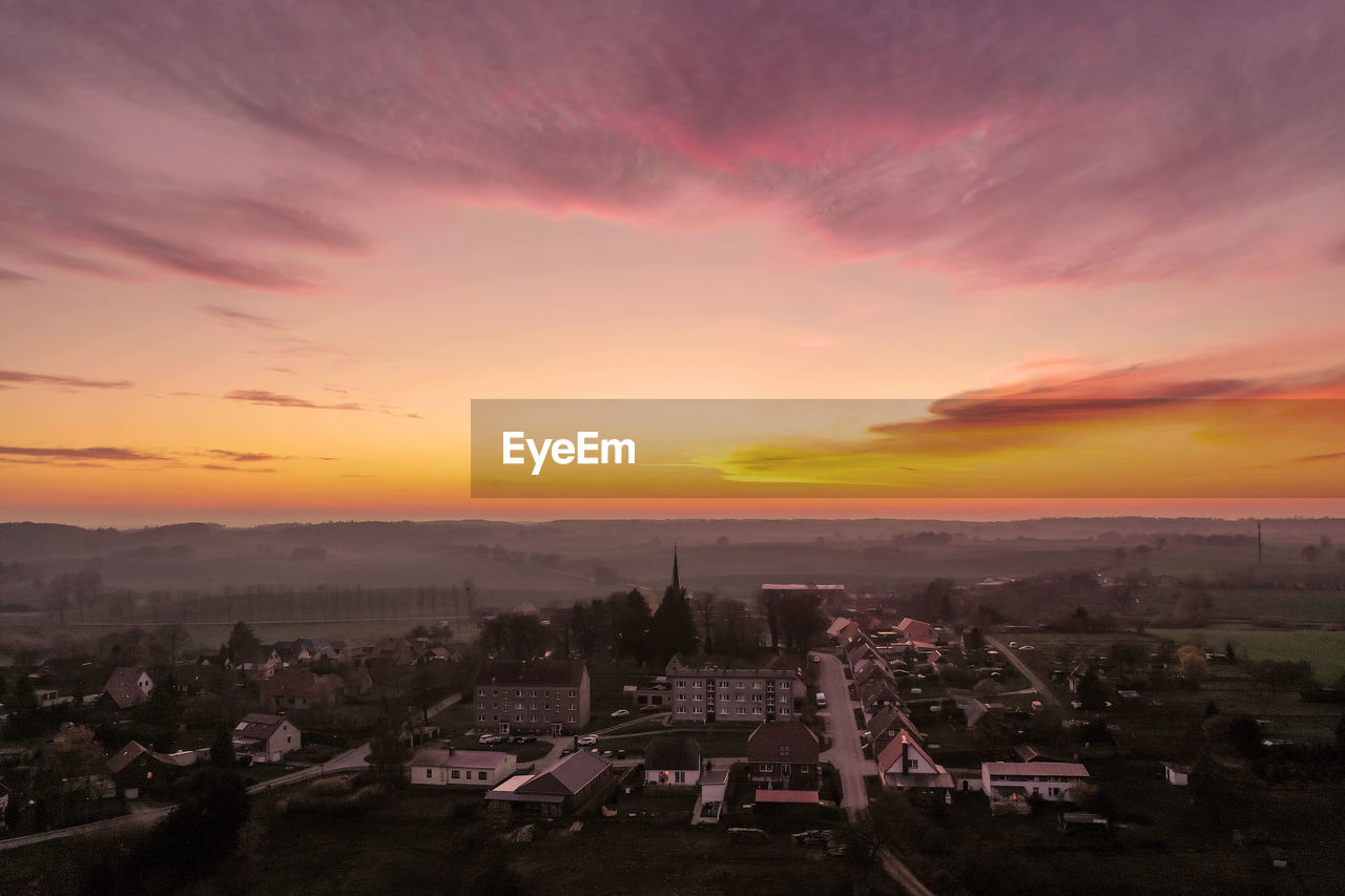 HIGH ANGLE SHOT OF TOWNSCAPE AGAINST ORANGE SKY