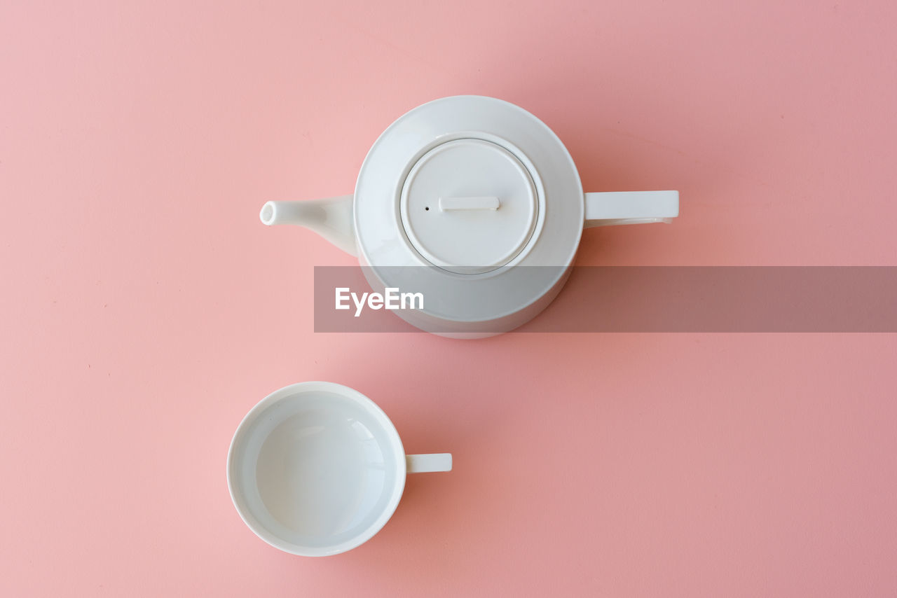 Directly above shot of tea cup and teapot against pink background