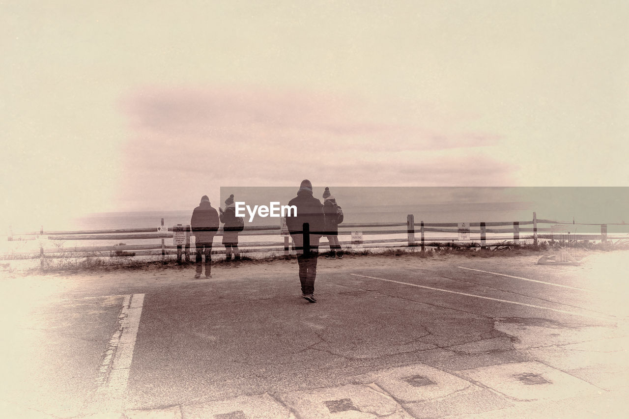 Double exposure of people at promenade by sea against sky