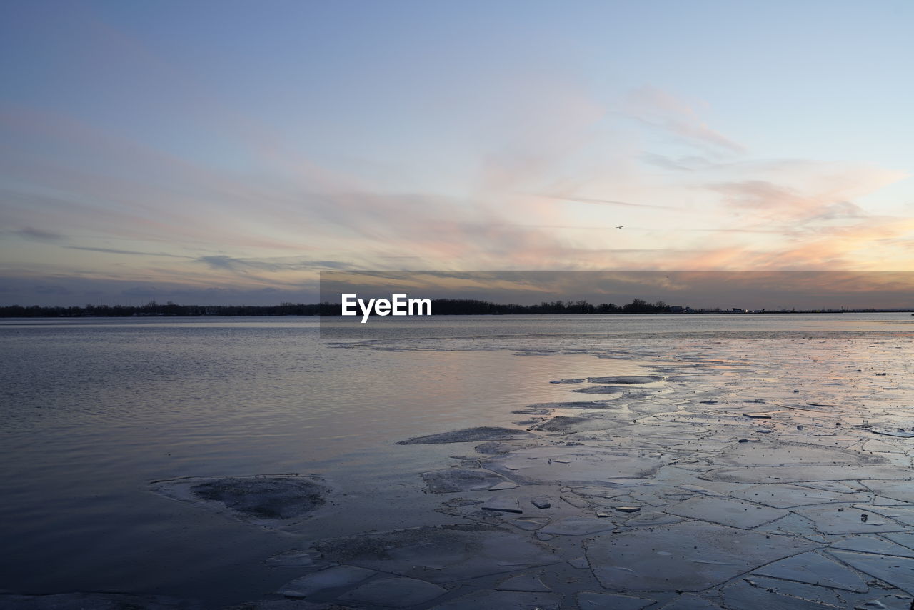 FROZEN LAKE AGAINST SKY DURING SUNSET