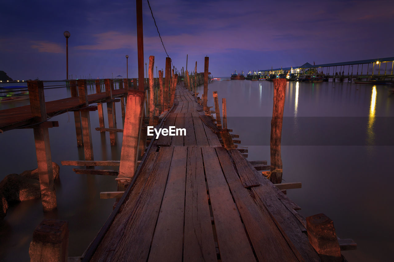 Pier over lake against sky at sunset