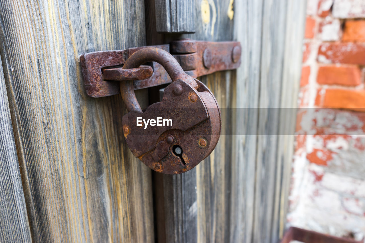 Close-up of rusty padlock hanging on door