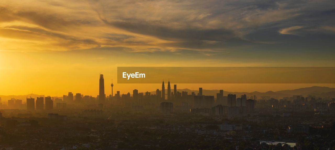 Buildings in city against sky during sunset