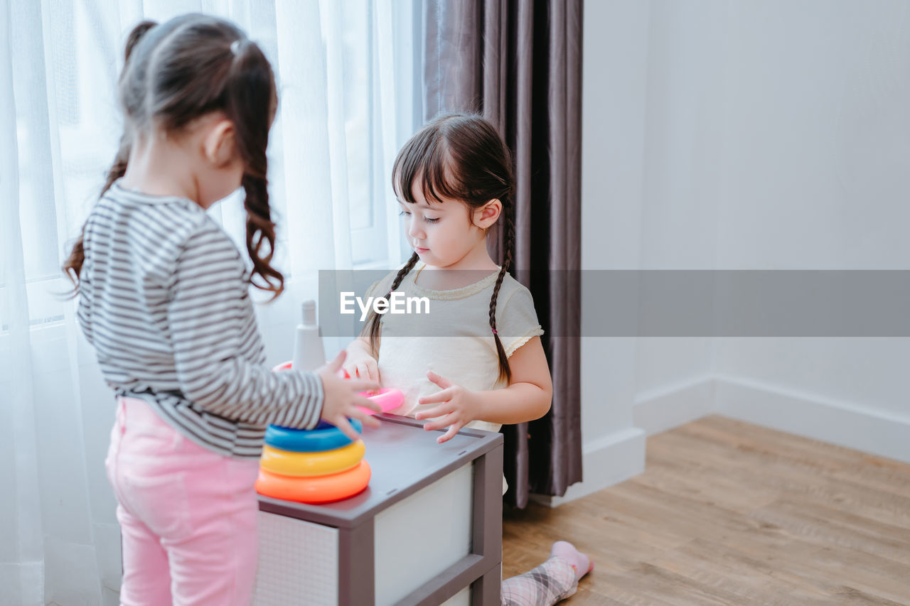 Sisters playing with multi colored toys at home