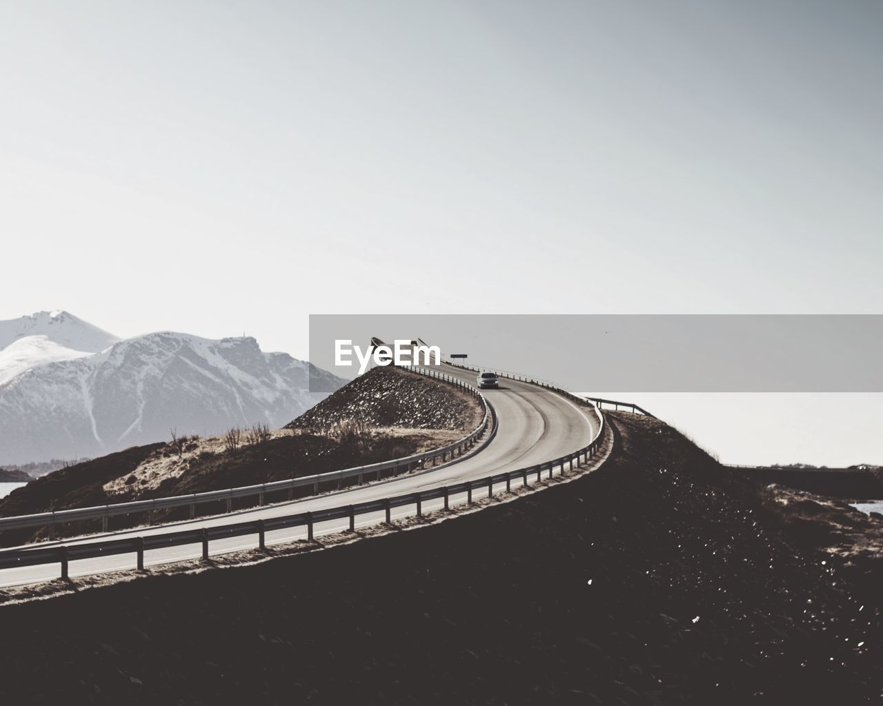 Road on mountain against clear sky during foggy weather