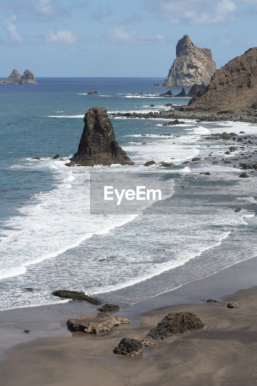 SCENIC VIEW OF ROCKY BEACH AGAINST SKY