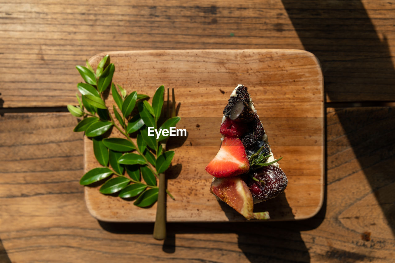 wood, food and drink, food, freshness, table, leaf, plant part, plant, healthy eating, nature, high angle view, no people, herb, produce, wellbeing, indoors, sunlight, still life, red, fruit, flower, shadow, green, berry, vegetable, art