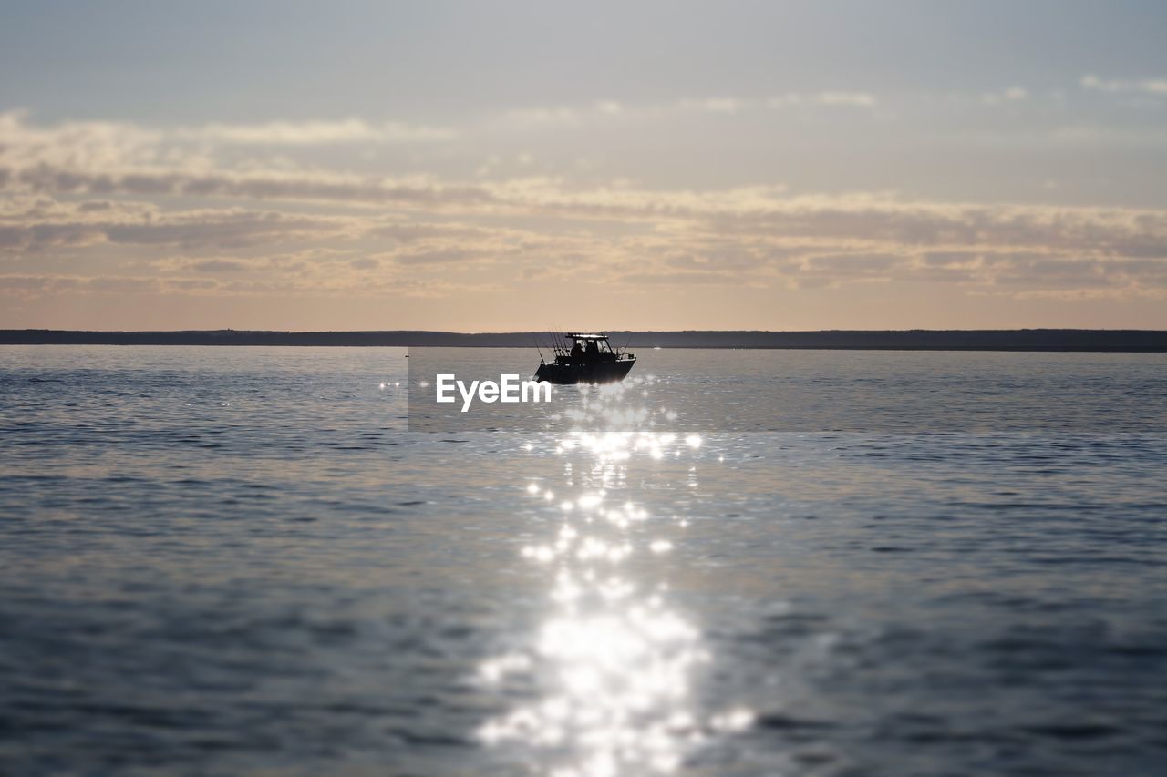 Boat sailing in sea against sky during sunset