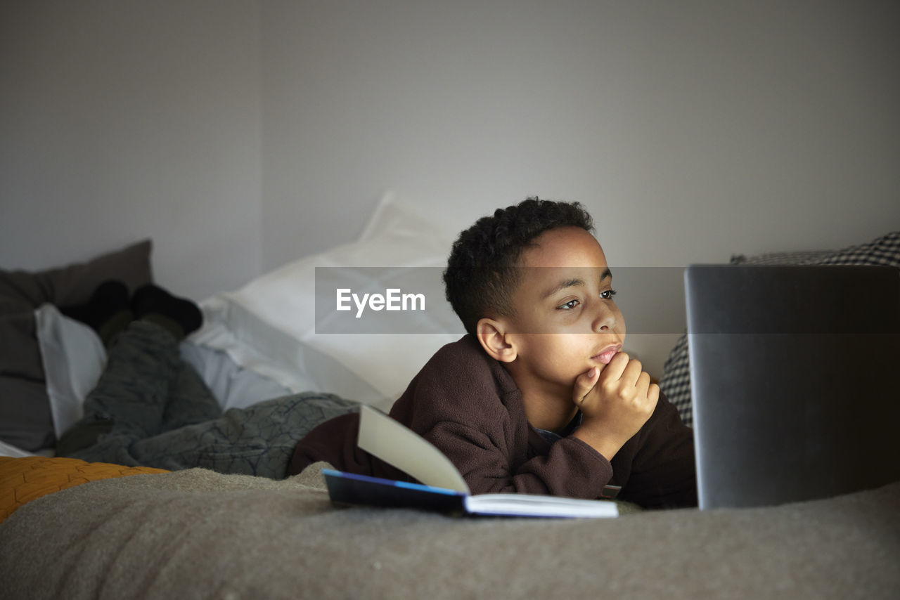 Boy doing homework with laptop in his bedroom