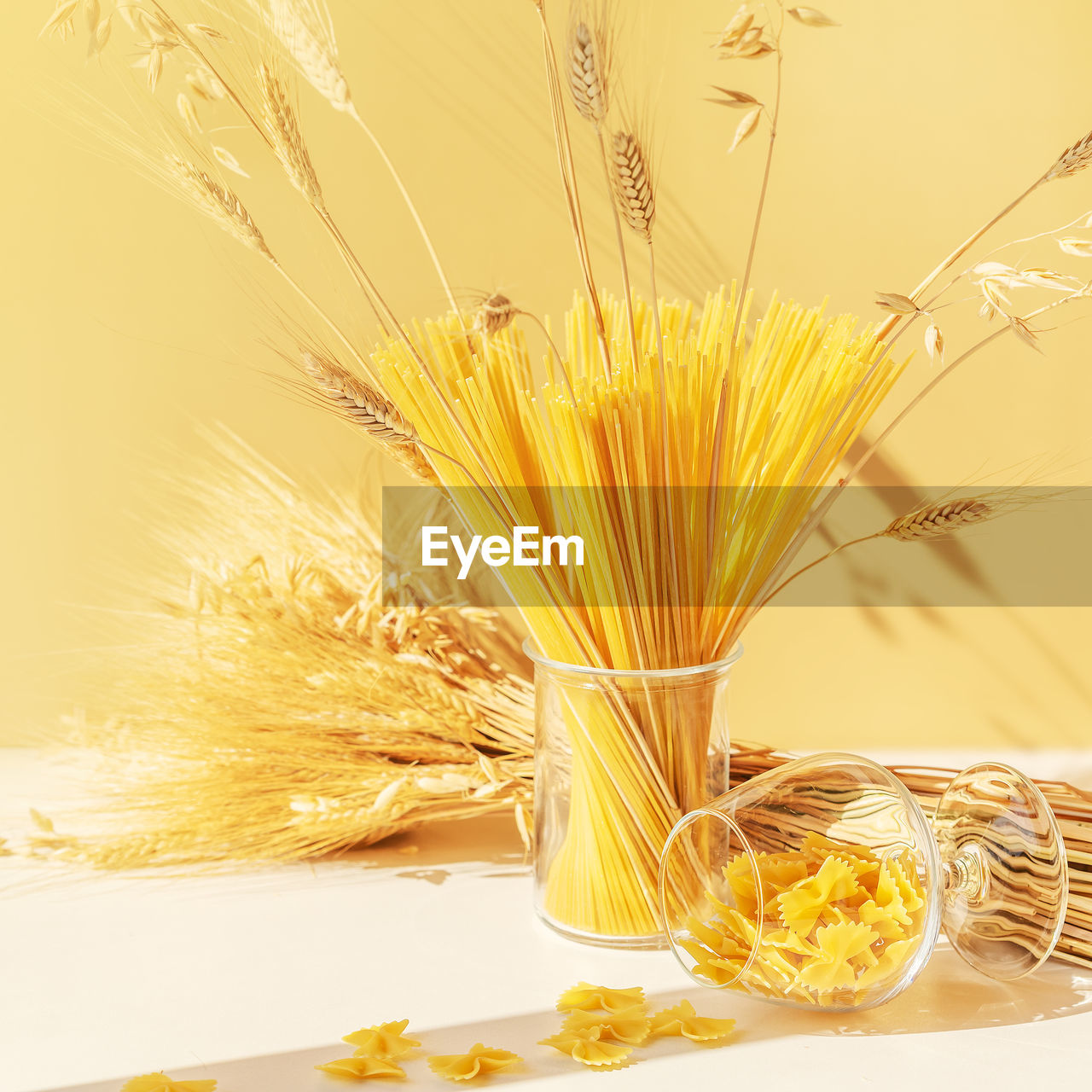 Raw spaghetti, farfalle pasta in a glasses with a bouquet of wheat. zero waste concept, no plastic