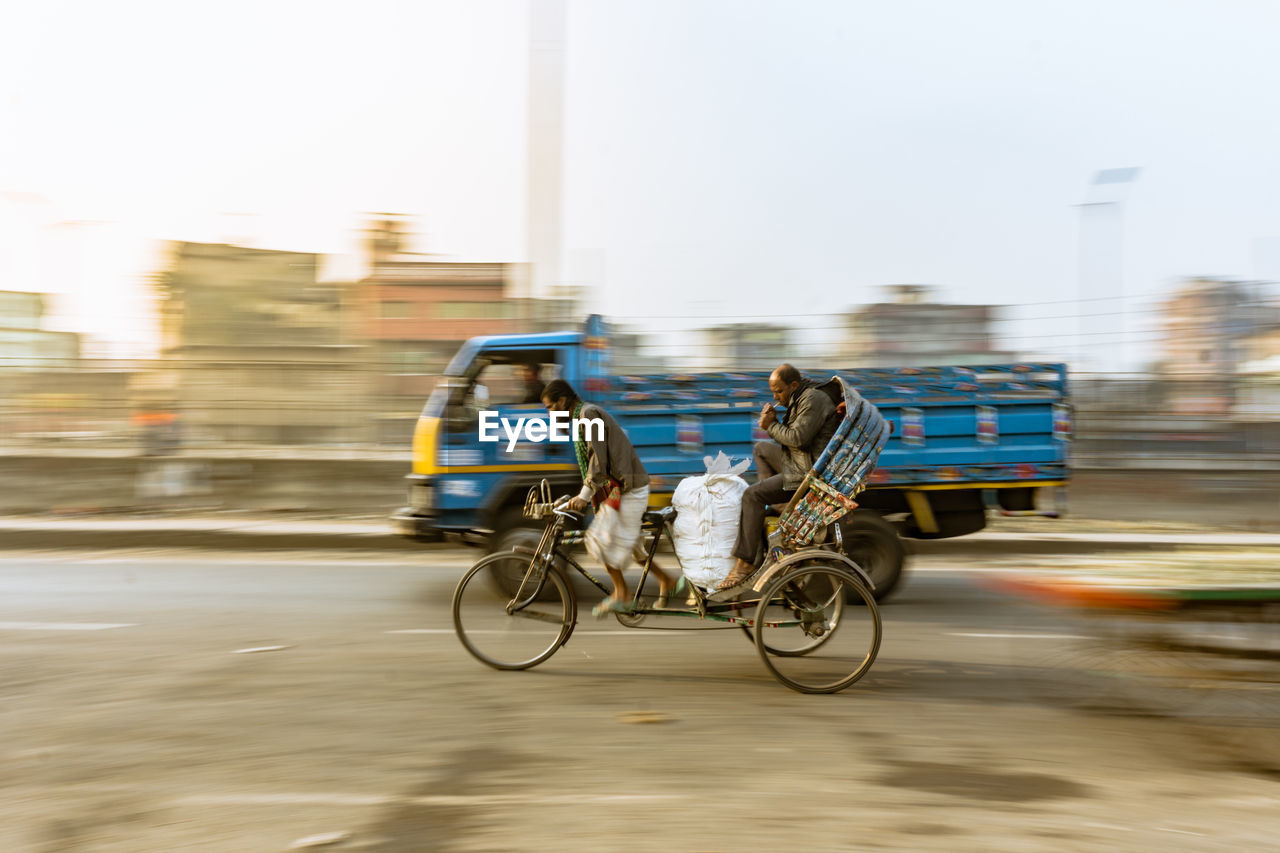 Rear view of man riding cycle rickshaw on street