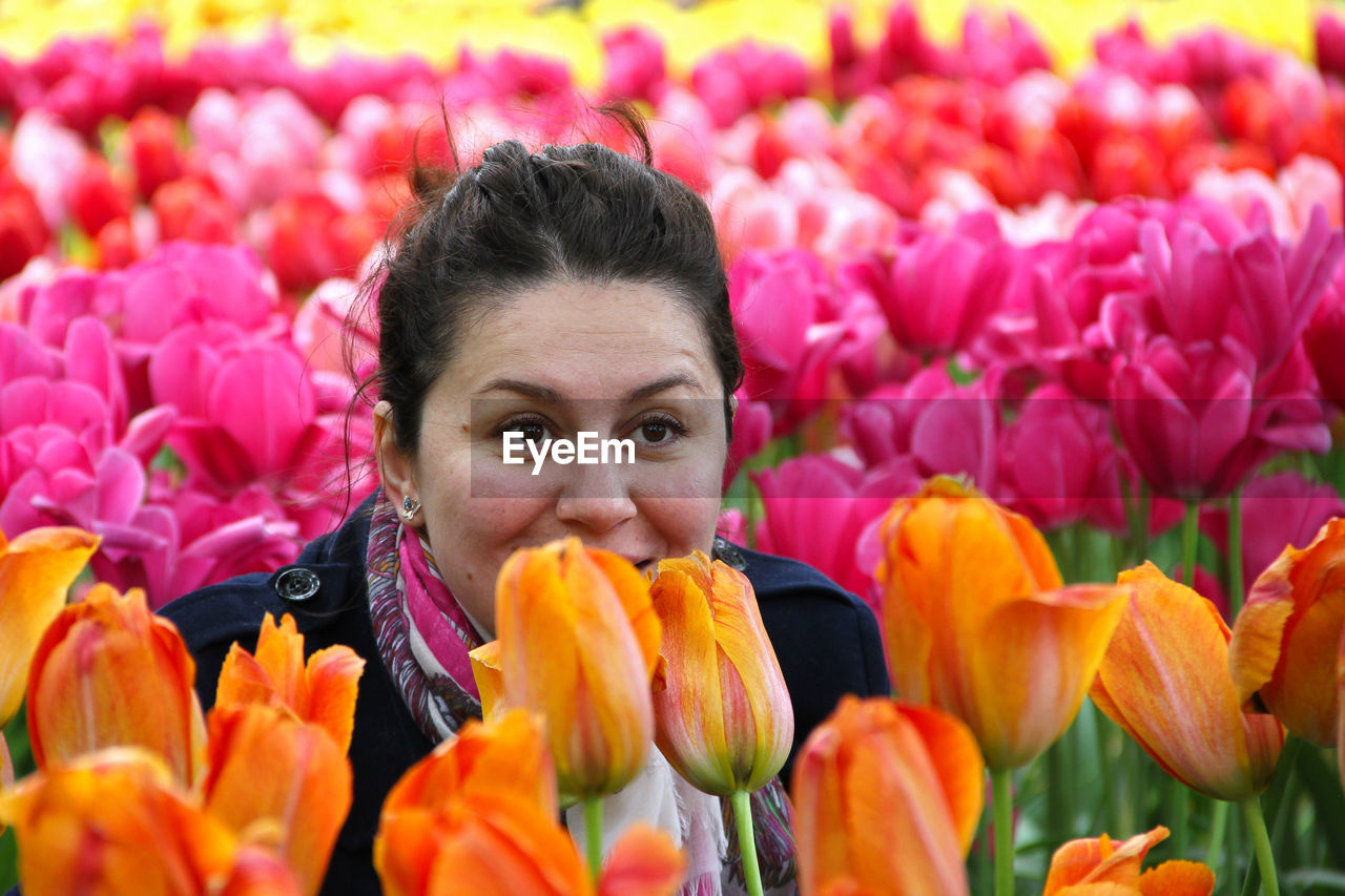 Smiling woman sitting amidst tulip field at park
