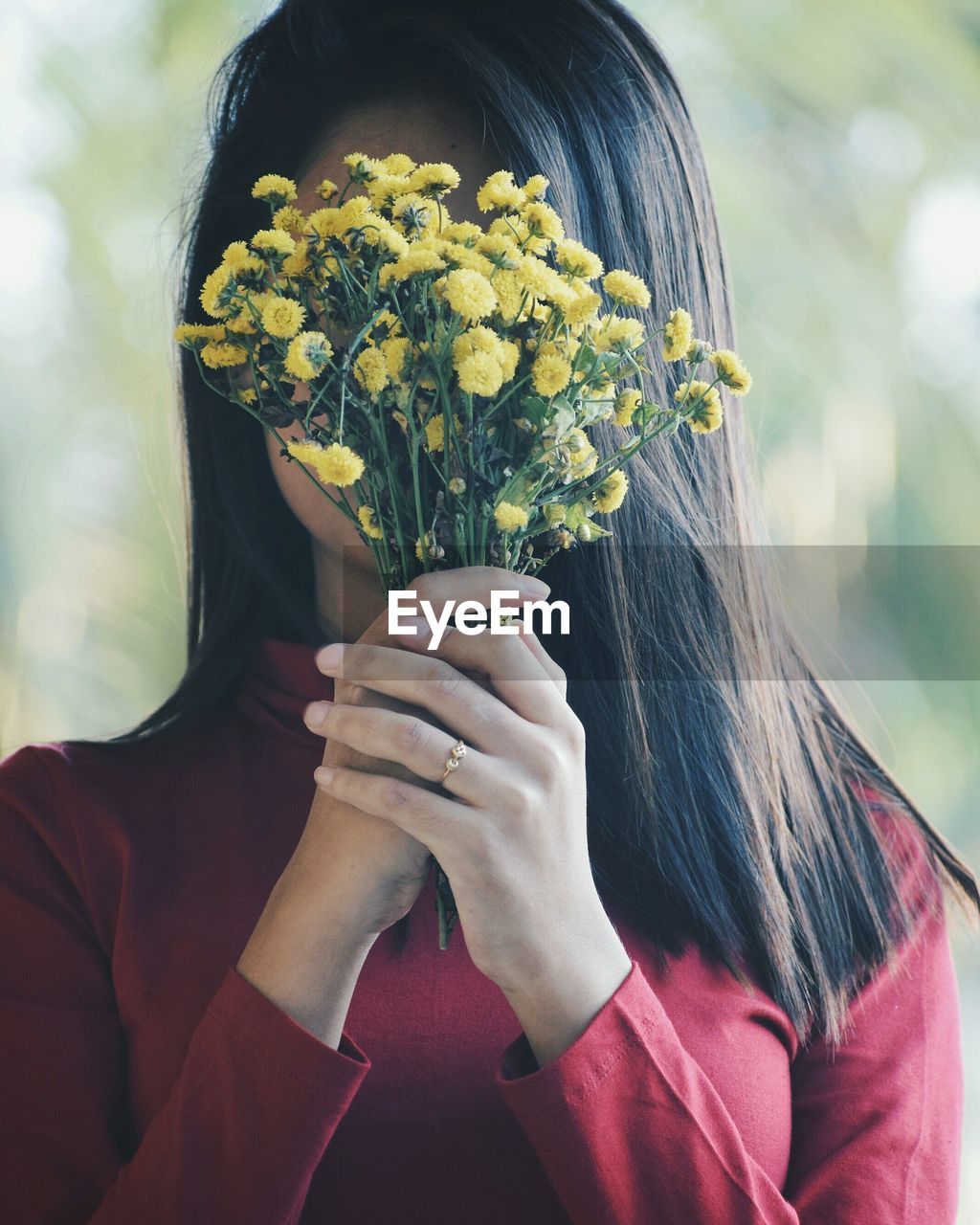 Woman holding flowers in front of her face