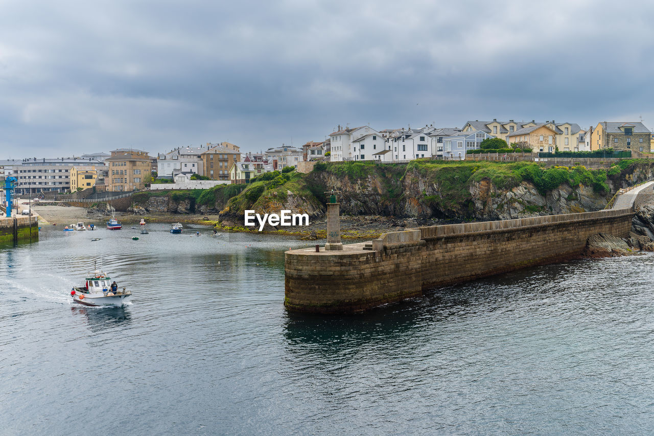 Boats in sea against cloudy sky