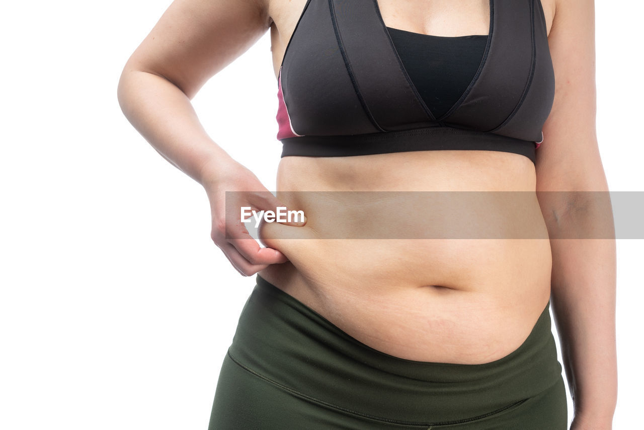 MIDSECTION OF WOMAN STANDING AGAINST BLACK BACKGROUND